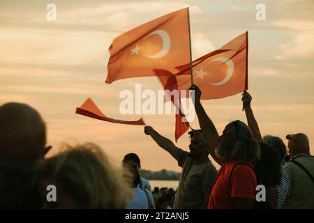 Izmir, Türkei, 9. September 2023, bei Sonnenuntergängen stehen vier Personen vereint und schwenken die türkische Flagge vor dem Hintergrund eines lebendigen Sonnenunterganghimmels Stockfoto