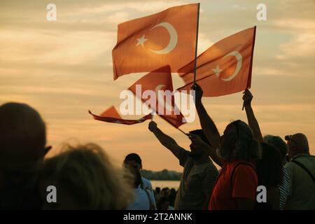 Izmir, Türkei, 9. September 2023, bei Sonnenuntergängen stehen vier Personen vereint und schwenken die türkische Flagge vor dem Hintergrund eines lebendigen Sonnenunterganghimmels Stockfoto