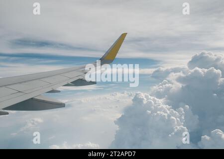 Ansicht des rechten Flügels vom Fenster des Flugzeugs, das in der Luft hochfliegt. Wolken im blauen Himmel. Flugzeug im Flug. Luftfahrt. Hintergrund von Flugreisen. Stockfoto