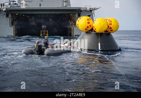NASA, Navy und Air Force üben Artemis II-Bergungsverfahren im Pazifischen Ozean während URT-10, Tag 5, vor San Diego aus. Navy-Taucher umgeben die Orion CMTA, während simulierte Astronauten von HSC-23 Hubschrauberpiloten zurückgeholt und zur USS John P. Murtha zurückgebracht werden. Stockfoto