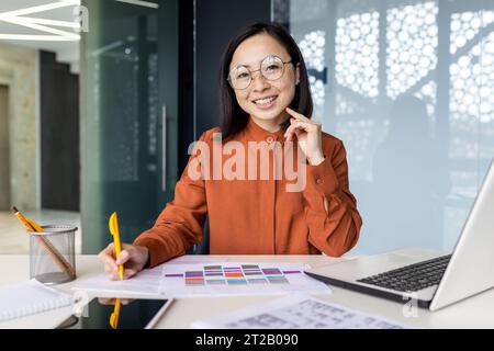 Porträt eines erfolgreichen asiatischen Finanziers, der Papierkram macht, Geschäftsfrau lächelt und in die Kamera blickt, Dokumente ausfüllt, Formulare am Arbeitsplatz ausfüllt, sich windet Stockfoto