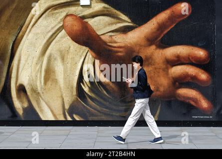 Fußgänger, der an einer großen Reproduktion eines Gemäldes von Caravaggio mit einer großen Greifhand auf einem Horten im Zentrum Londons, England, vorbeigeht Stockfoto