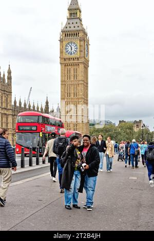 Zwei Afroamerikanerinnen machen ein Selfie auf der Westminster Bridge mit dem roten Londoner Bus und Big Ben hinter ihnen, Central London England Stockfoto