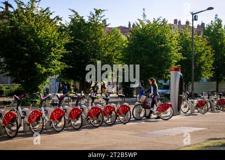 Frau wählt ein Fahrrad aus dem Velo'v Fahrradservice-Rack in Lyon, Frankreich. Stockfoto