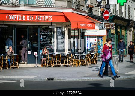 Menschen, die in einem Restaurant im Freien im Viertel Le Marais in Paris, Frankreich, spazieren gehen und sitzen. Stockfoto