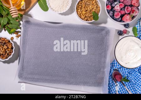 Kochen Herstellen gefrorener Joghurtrinde Hintergrund mit griechischem Joghurt, frischer Beere, Müsli, Honig, Schokoladensauce, mit Backblech Deko. Blick von oben auf die Frau Stockfoto