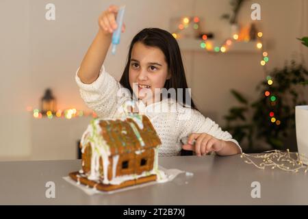 Ein Mädchen spielt mit einem Lebkuchenhaus für traditionelle Weihnachtsdekoration Stockfoto