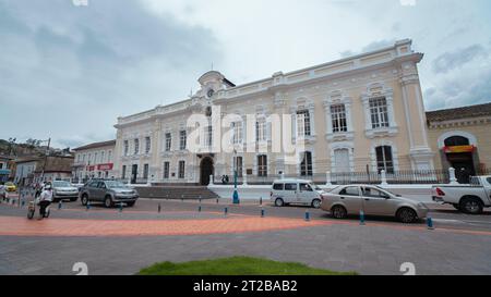 Otavalo, Imbabura/Ecuador - 14. Oktober 2023: Fahrzeuge fahren an einem bewölkten Tag vor dem Gebäude der Stadtverwaltung Stockfoto