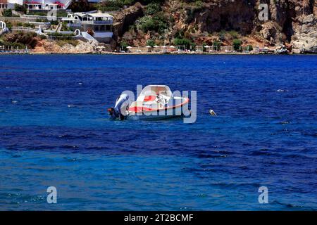Kleines rot-weißes Boot mit Außenbordmotor, in Livadia Bay, Tilos. Mai/Juni 2023. Stockfoto