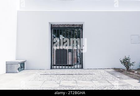 Eisentor in weißer Mauer in der Altstadt von Faro, Algarve, Portugal Stockfoto