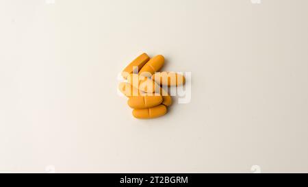 Multivitamin-Ergänzungspillen vor einem neutralen cremeweißen Hintergrund. Stockfoto