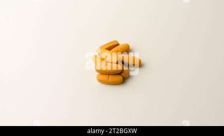 Multivitamin-Ergänzungspillen vor einem neutralen cremeweißen Hintergrund. Stockfoto