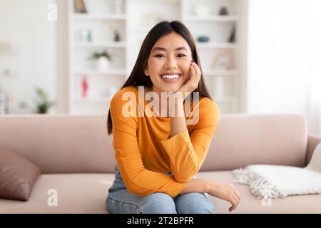 Porträt einer fröhlichen jungen asiatischen Frau, die zu Hause posiert Stockfoto