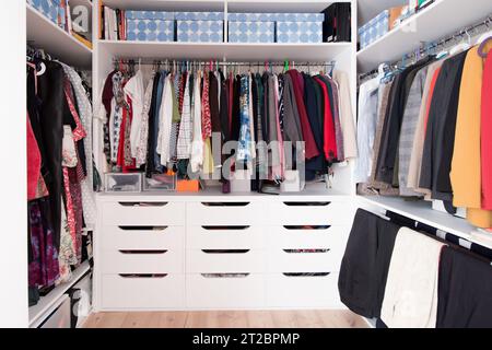 Ein wandelnder Kleiderschrank voller Frauenkleidung. Weiße Holzmöbel Stockfoto