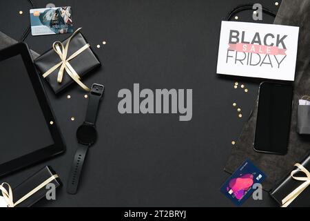 Komposition mit Black Friday Grußkarte, Geschenkboxen und Gadgets auf dunklem Hintergrund Stockfoto