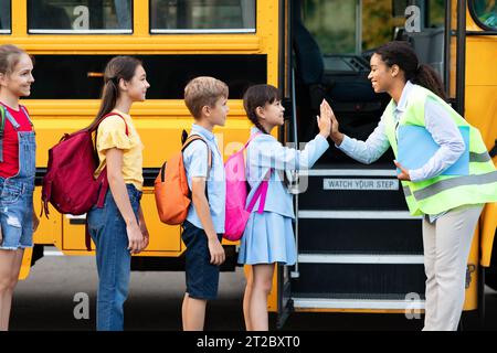 Der Kinderinternat-Schulbus erhält fröhliche High-Five von einem lächelnden schwarzen Lehrer Stockfoto