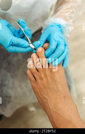 Orthopädischer Arzt in blauen Handschuhen bei der Behandlung der Beine, Nahaufnahme, vertikaler Schuss Stockfoto