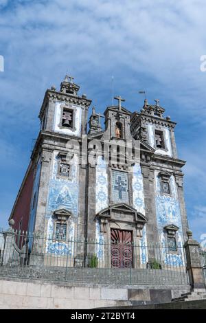 Historische portugiesische Kirche mit verzierten blauen Azulejo-Fliesen und zwei Glockentürmen vor bewölktem Himmel Stockfoto