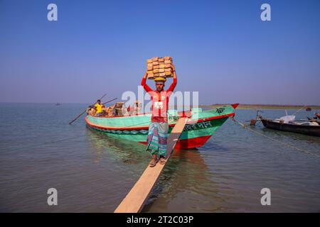 Arbeiter, die Ziegelsteine von einem Boot am Ufer des Meghna River in Chandpur, Bangladesch, entladen. Stockfoto