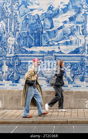 Menschen, die an den Capela das Almas Azulejo Tiles in Porto, Portugal, vorbeilaufen Stockfoto