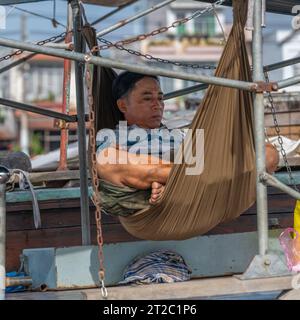 Mann in der Hängematte auf dem Boot auf dem schwimmenden Markt, Vietnam Stockfoto