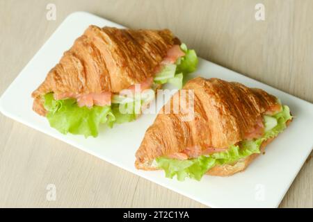 Sandwiches mit Croissants, Fischfleisch und grünem Salat auf einem Brett. Stockfoto