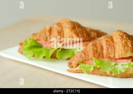 Sandwiches mit Croissants, Fischfleisch und grünem Salat auf einem Brett. Stockfoto