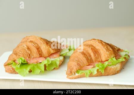 Sandwiches mit Croissants, Fischfleisch und grünem Salat auf einem Brett. Stockfoto