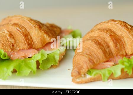 Sandwiches mit Croissants, Fischfleisch und grünem Salat auf einem Brett. Stockfoto