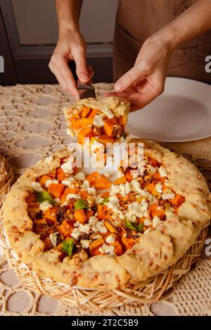 Hausgemachte Bäckerei - offener Kürbiskuchen, Nahaufnahme eines Stücks Schnittkuchen in Frauenhänden Stockfoto