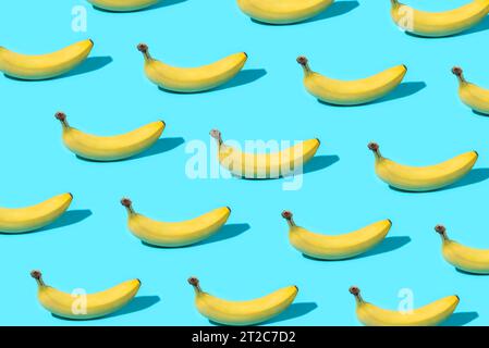 Trendiges Sommer-Food-Muster mit gelben Bananen auf hellblauem Hintergrund. Minimales Sommerkonzept. Stockfoto
