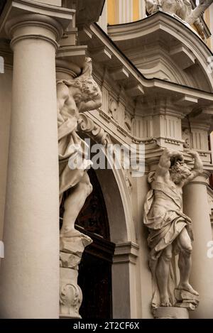 Atlas hält gebrochenen Giebel unter leichtem Schnee im barocken Kinsky-Schloss in Wien, Österreich. Stockfoto