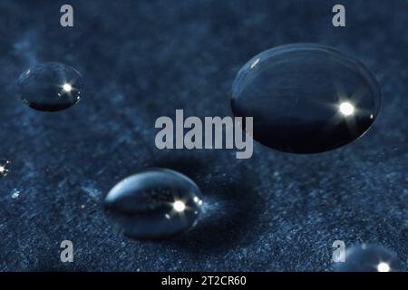 Wassertropfen auf Glas vor dunkelgrauem, strukturiertem Hintergrund. Makrofotografie Stockfoto