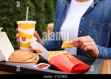 Lviv, Ukraine - 9. Oktober 2023: Frau mit McDonald's Menü am Tisch draußen, Nahaufnahme Stockfoto