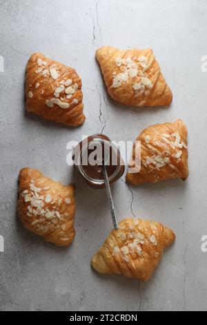 Leckere Croissants mit Mandelflocken und Schokoladenpaste auf grauem Tisch, flach gelegt Stockfoto