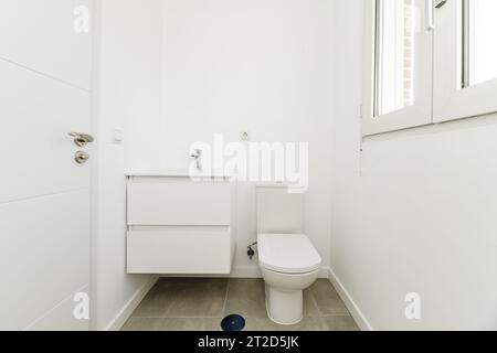 Kleines Badezimmer in einem Haus mit einem weißen Porzellanwaschbecken an der Wand mit Holzschubladen Stockfoto