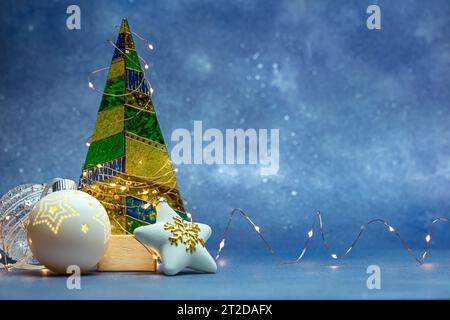 weihnachts- oder Neujahrskarte. weihnachtstanne mit Weihnachtsbeleuchtung und weihnachtsschmuck auf blauem Hintergrund. Stockfoto