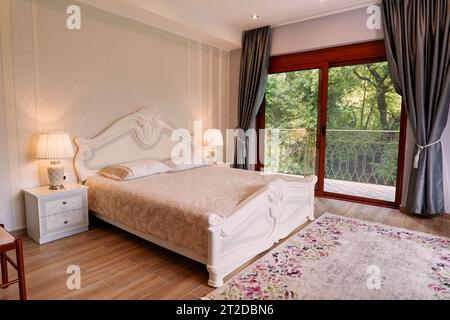 Doppelbett aus weißem Holz im Hotelzimmer mit Panoramafenster Stockfoto