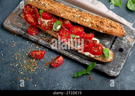 Frisches Baguette mit Caprese. Köstliches Sandwich mit Tomaten und Mozzarella mit frischen Basilikumblättern. Italienisches Essen. Stockfoto