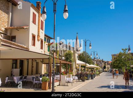 Grado, Italien - 11. August 2023. Eine der wichtigsten Fußgängerstraßen, gesäumt von Bars und Restaurants, im historischen Zentrum von Grado, an der Küste von N.E. Italien Stockfoto