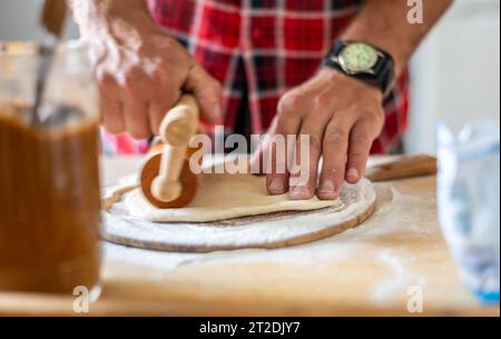 Details der Hände von Männern, die den Teig Rollen. Zubereitung zum Backen von traditionellem tschechischem Gebäck. Hausgemachte frische Speisen Stockfoto