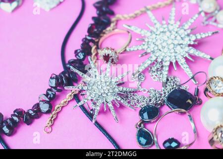 Wunderschöner Schmuck schimmernd glamouröser Schmuck Set, Halskette, Ohrringe, Ringe, Ketten, Broschen mit Perlen und Diamanten auf pinkfarbenem Lila Stockfoto