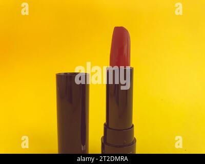 Lippenstift in einer schwarzen Kompaktverpackung auf gelbem mattem Hintergrund. Leuchtend roter Lippenstift, Schattierung, Lippenhydratisierung. Stylischer und trendiger Farbton. Stockfoto