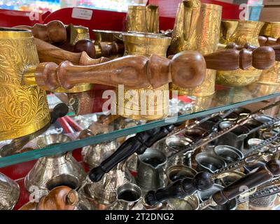 Wunderschöne goldene türkische türken mit einem Holzgriff zum Brühen von Kaffee glänzende orientalische Dekoration in einem Touristensouvenirladen. Stockfoto