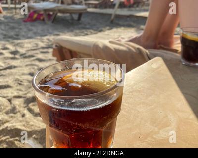 Ein Glas mit einem alkoholfreien Getränk brauner Cocktail mit Limonade und Whiskey auf einem Tisch am Strand am Meer in einem Hotel im Urlaub in einem Paradies warmen östlichen tr Stockfoto