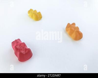 Gummibären auf weißem mattem Hintergrund. Rot, gelb und orange liegen auf dem Tisch. Leckere Süßigkeiten, Leckereien von Menschen. Süßigkeiten unserer eigenen Produkte Stockfoto