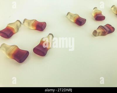 Die Buchstaben sind auf einem gelben, matten Marmeladehintergrund angeordnet. Gelatinesbonbons in Form von Flaschen mit Limonade. Valentinstag. Kreativ süß und e Stockfoto