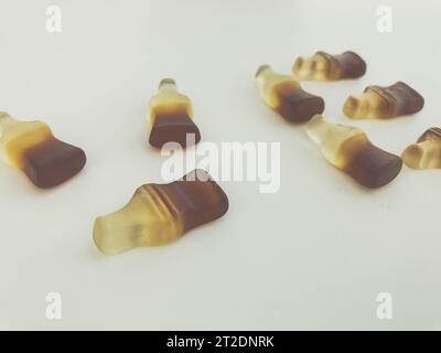 Die Buchstaben V und E sind auf einem gelben, matten Marmeladehintergrund angeordnet. Gelatinesbonbons in Form von Flaschen mit Limonade. Valentinstag. Kreativ Stockfoto