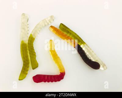 Gummiwürmer liegen auf weißem, mattem Hintergrund. Helle, mundtränende gelatinöse Würmer unterschiedlicher Farben. Köstliches und süßes Dessert. Köstliche Süßigkeiten Stockfoto