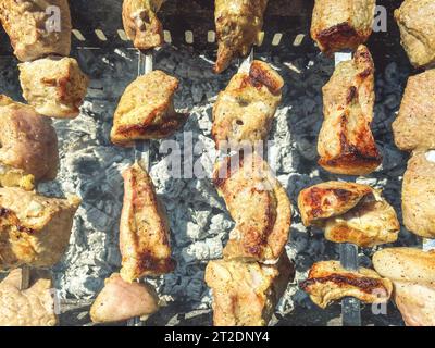 Fleischspieße liegen auf dem Grill. Eine Kruste wird auf Fleischstücken gebacken. Gegrillte Gerichte, Grill, herzhafte Mahlzeiten für eine Gesellschaft von Menschen. Stockfoto